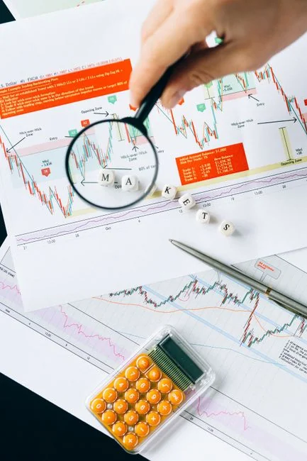Two businessmen analyze stock market data using a smartphone and laptop in a modern office setting.